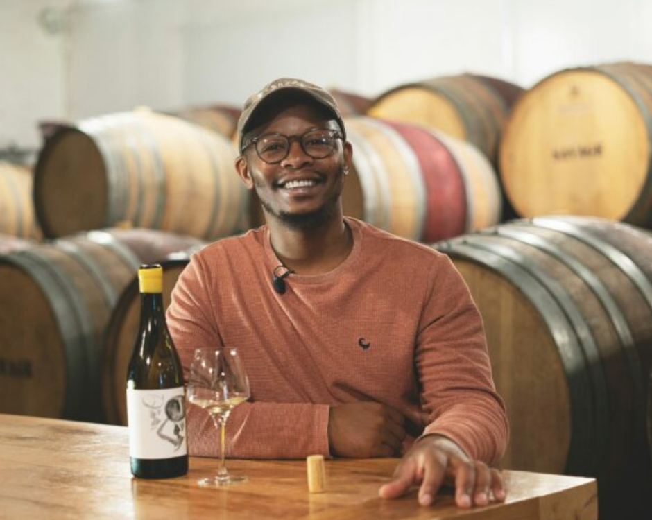 Banele Vakele, one of the contestants of the show, sitting down with a glass of wine and bottle in front