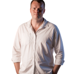 Janco de Kock in a white shirt with hands in pockets, looking at the camera.